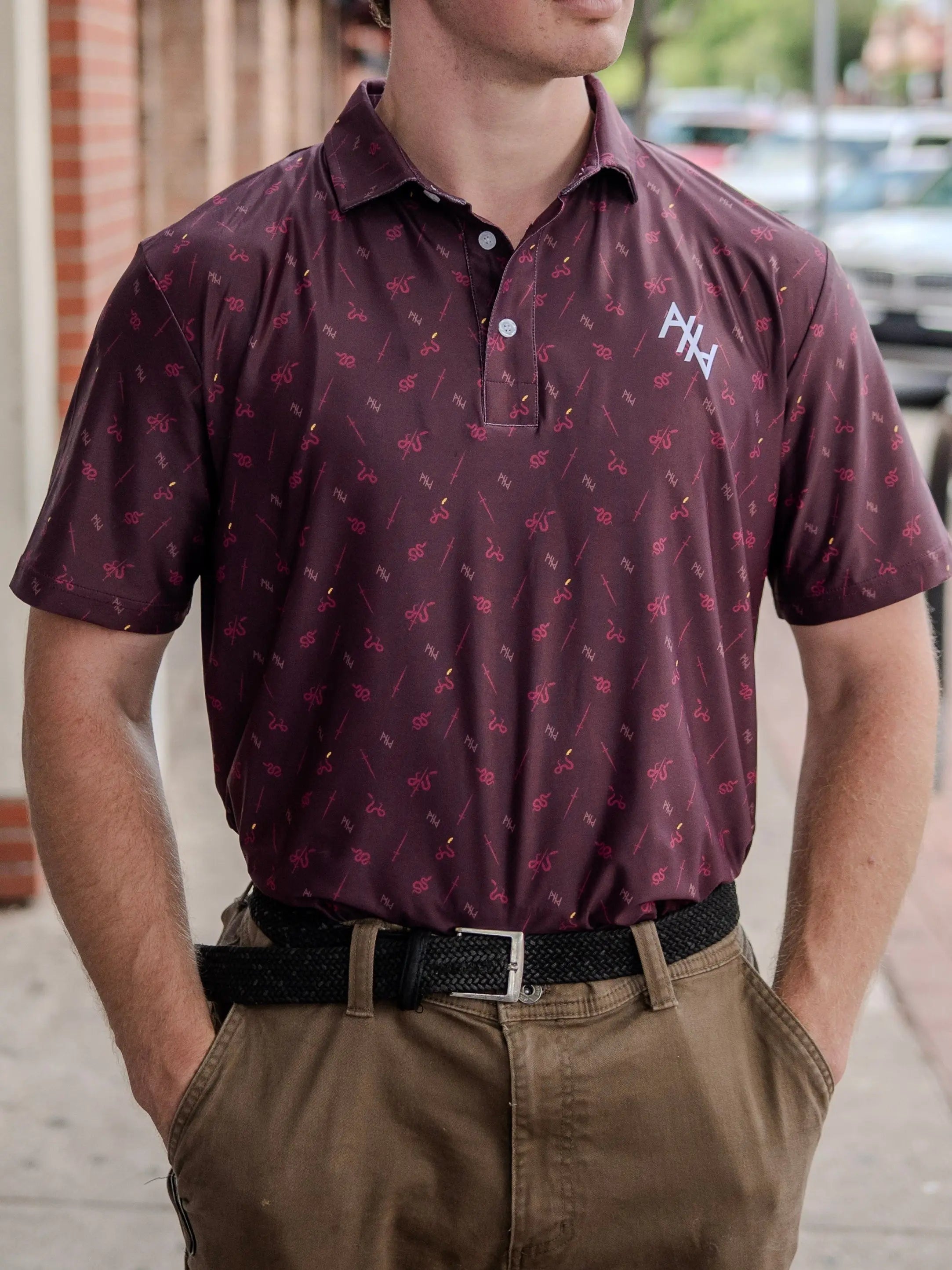 Man wearing a maroon Abolitionists Rising polo shirt with a logo on a city street