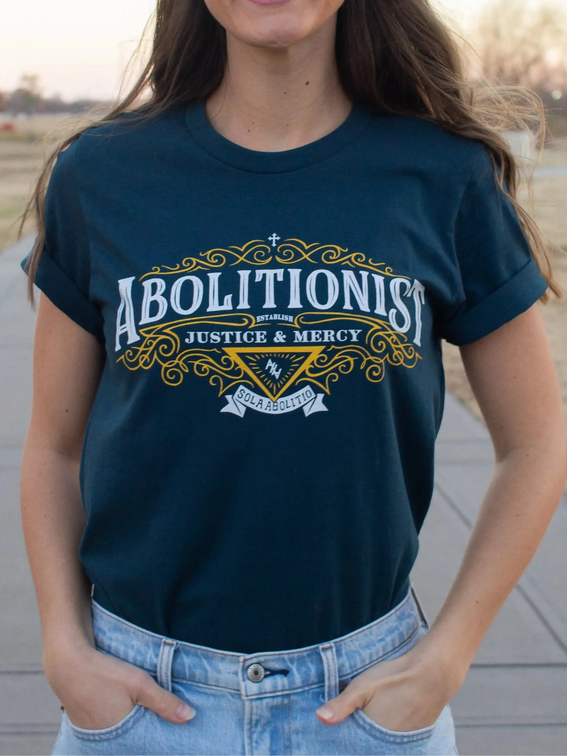 Woman wearing a atlantic t-shirt with 'Abolitionist' design, standing outdoors.